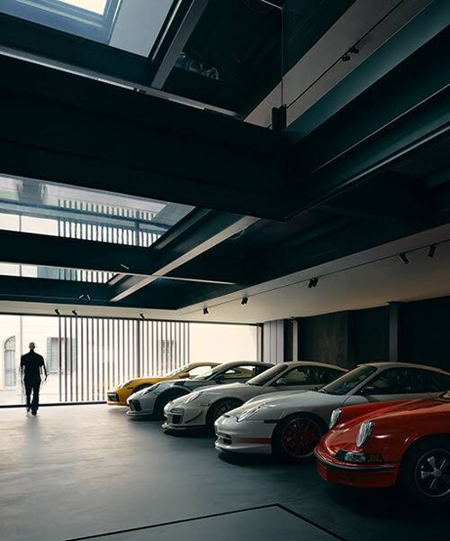 A black resin and steel living space featuring a vehicle platform with an automobile displayed near a modern dining area.