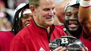 Indiana head coach Curt Cignetti speaks at a podium during Big Ten media days with a championship trophy beside him.