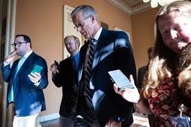 Senate Majority Leader John Thune walking through the U.S. Capitol while speaking to reporters.