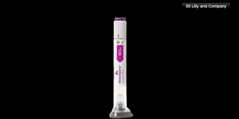 A clinical close-up of a Mounjaro injection pen held in a medical environment.