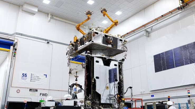 Robotic arms on a spacecraft in a clean room during assembly for the Northrop Grumman mission.