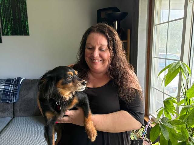 Marie Noon sits in her living room with her dog, highlighting a case where Medicaid errors caused significant health coverage issues.