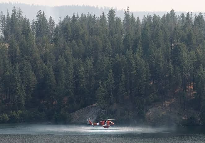 A Black Hawk firefighting helicopter draws water from the Spokane River to suppress the Charles fire near Spokane.