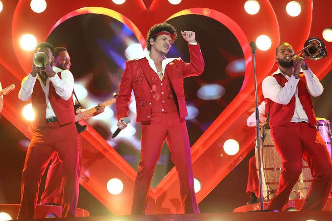 Bruno Mars performing on stage in a red suit during the opening of The Romantic Tour at MetLife Stadium.