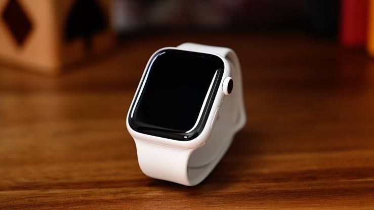 Close-up of an Apple Watch Series 5 with a white ceramic case shown on a neutral background.