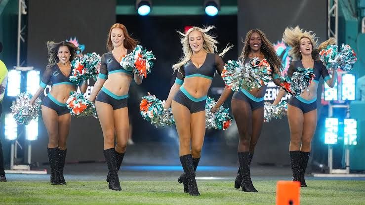 Miami Dolphins cheerleaders performing a dance routine for fans at Hard Rock Stadium during an NFL game.