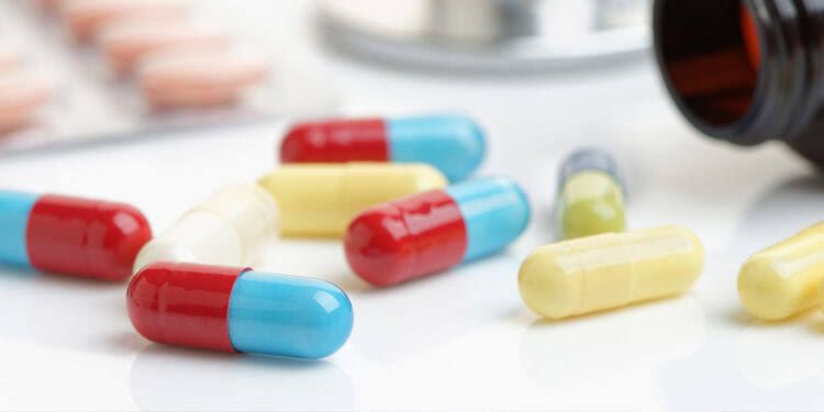 A close-up of a prescription pill bottle and a urine sample cup on a sterile clinic desk.