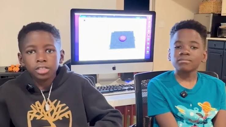 Aaron and Alain Osirus showing their 3D-printed toys during a news interview.