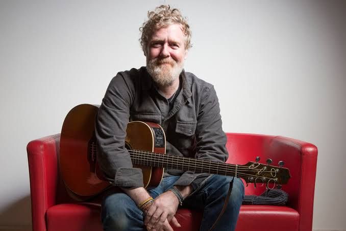 Glen Hansard performing on stage with a guitar at the Auditorium Parco della Musica in Rome.