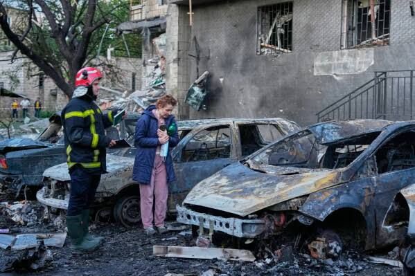Debris surrounds a large missile crater in front of a damaged building in Kyiv following a Russian strike.