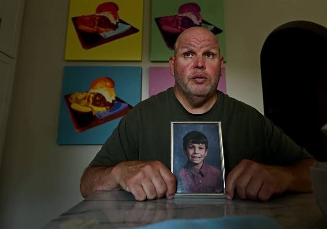 Raymond Scott Mikesell holds a memorial book for his son, Ray, who died due to a sports gambling addiction.