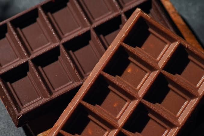 Two dark chocolate bars placed on a surface before a gym workout.
