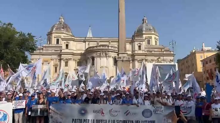 Thousands of uniformed Italian police and military personnel march together through the streets of Rome during a protest.