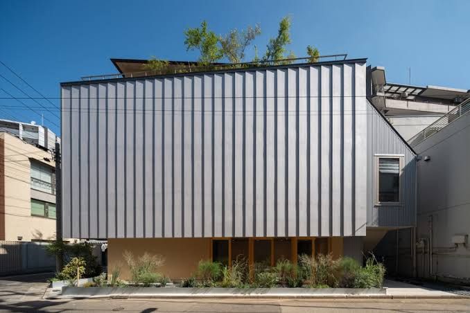A four-story steel-frame Tokyo Ballet House with a glazed facade showing a studio space from the street level.