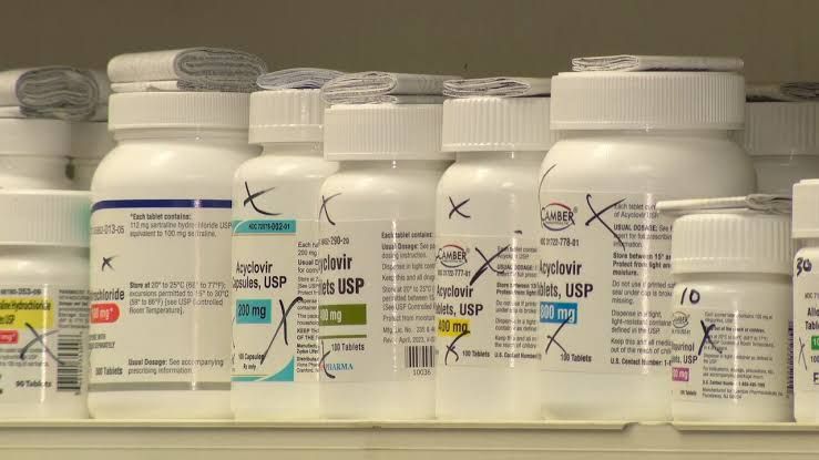 A pharmacist stands behind a counter at an independent pharmacy in Georgia during a local news segment.