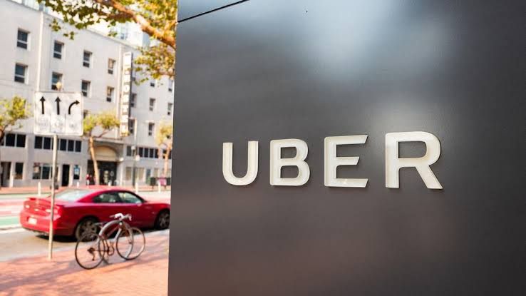 Uber logo displayed on a digital screen near a company office building during the 2026 restructuring announcement.
