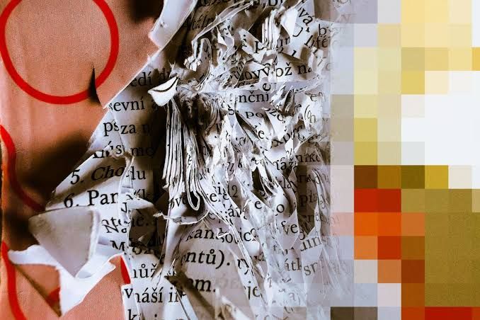 Torn pages from a printed book lie on a surface alongside colorful graphical shapes and pixelated blocks of yellow and orange.
