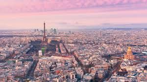 Aerial view of Paris at night showing illuminated buildings and streets under a dark blue sky.