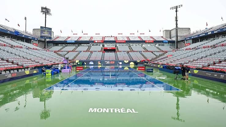 Wet tennis courts at the National Bank Open in Montreal under heavy rain during a suspended match.