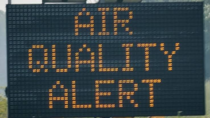 An Air Quality Alert sign displayed on a street in Central New York against a hazy, yellow-tinted sky.