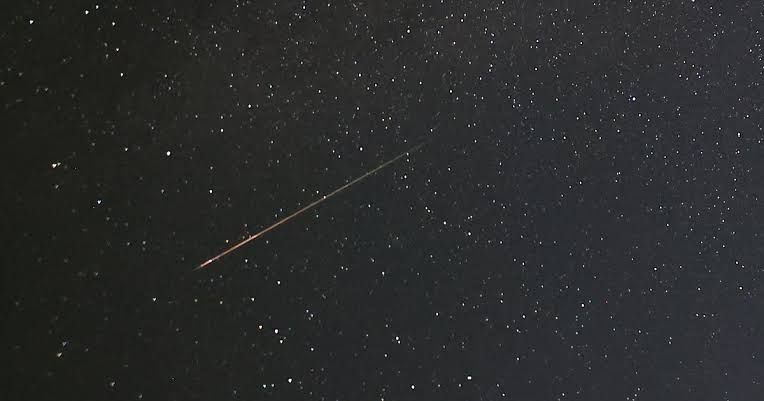 Bright light streaks from the Perseid meteor shower visible against a dark, starry night sky.