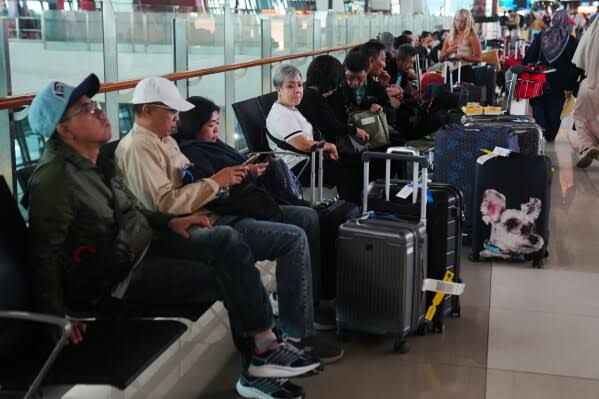 Travelers wait in a terminal at Soekarno-Hatta International Airport following flight cancellations due to volcanic ash.