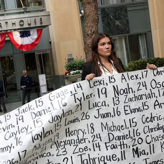 A woman holds a sign listing names of children in front of an Oakland courthouse to protest social media safety.