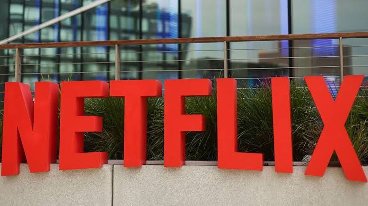 Netflix logo displayed on a digital screen alongside financial market charts and trading data.