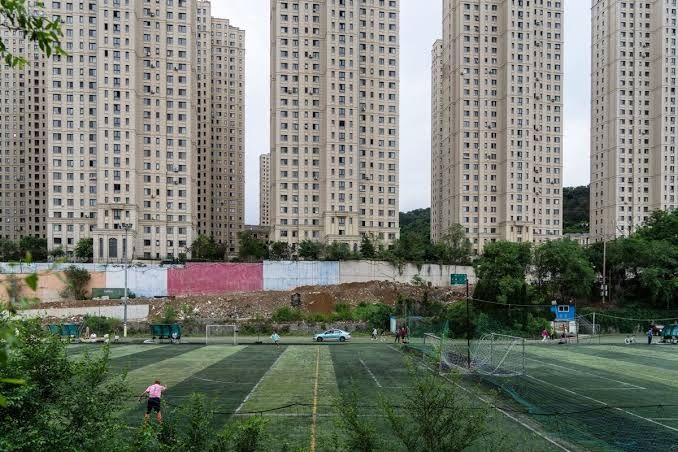 A construction site in China featuring multiple unfinished residential high-rise buildings against a city skyline.