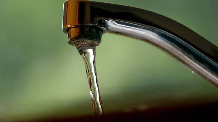 Close-up of a clear glass of water next to a kitchen faucet, representing residential water safety.