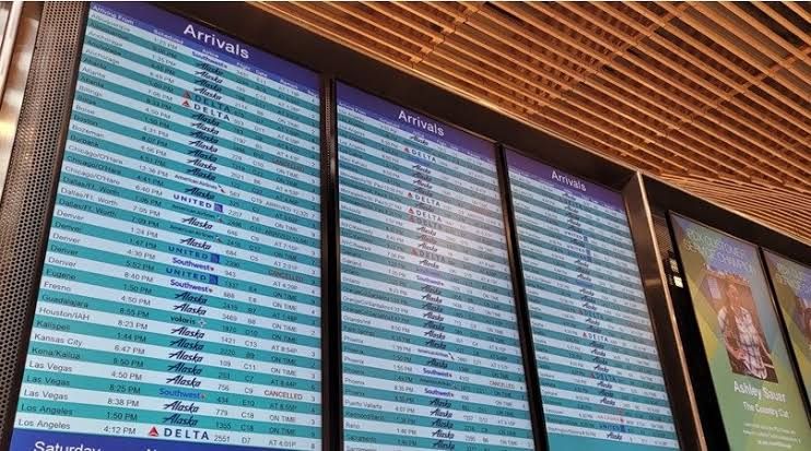 Airport terminal with digital flight status boards showing delays due to network connectivity issues.