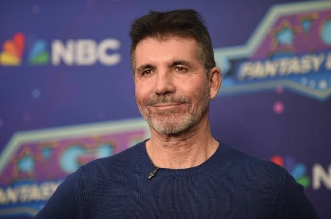 Simon Cowell sitting at the America's Got Talent judging panel during a live show taping.