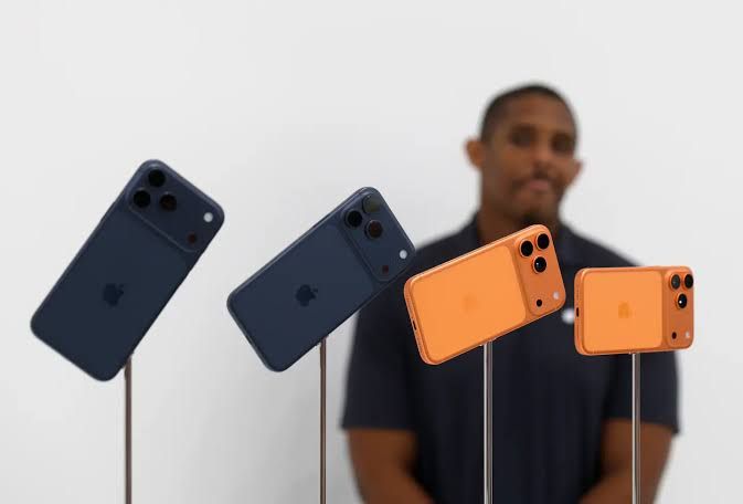 A close-up of a person holding the latest iPhone model in a retail store setting.