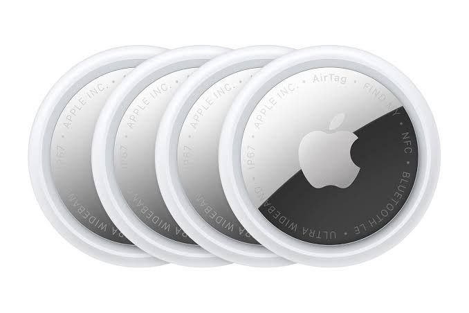 A close-up of four Apple AirTag 2 devices arranged in a square on a white background.