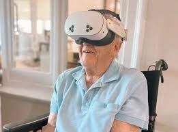 An elderly man wearing a virtual reality headset during an immersive motorcycle racing simulation experience.