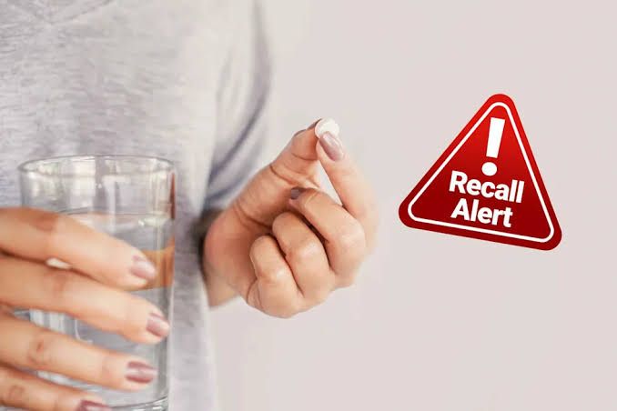 Close-up of prescription medication bottles on a pharmacy counter with a blurred medical setting in the background.
