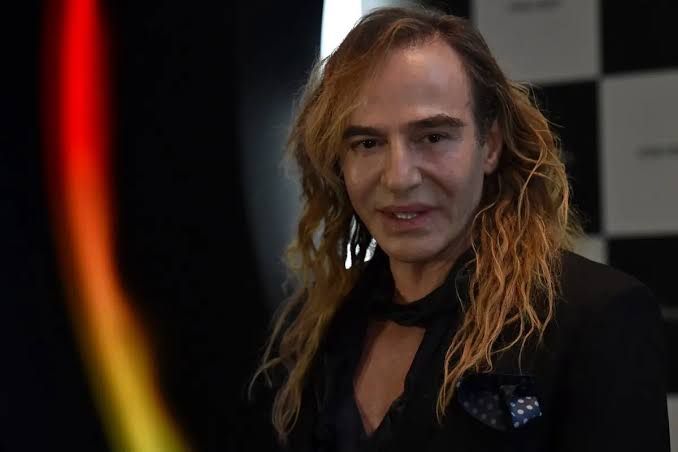 John Galliano walking a runway during a fashion show, representing his career at Christian Dior.