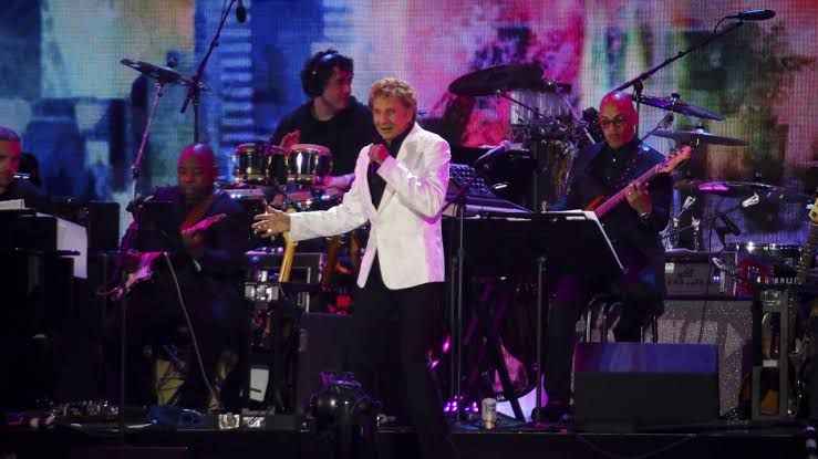 Barry Manilow performing on stage at an outdoor concert venue during a public music event.
