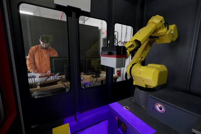 An employee works in a 3D scan lab, highlighting technical roles emerging in manufacturing.