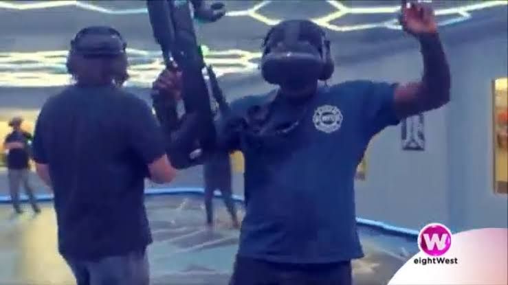A promotional shot of a player wearing a VR headset and backpack in a 1000-square-foot gaming arena.