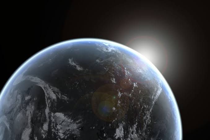 The sun rises over the curved horizon of the Earth with a blue atmosphere visible against the darkness of space.