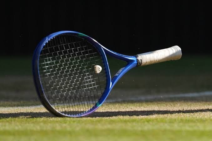 A single tennis racket rests on a grass court at the Wimbledon Championships.