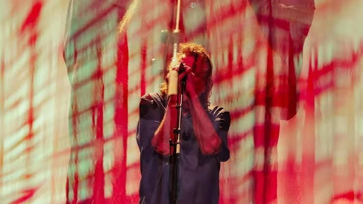 Robert Plant standing on stage during a musical performance at the Ryman Auditorium.