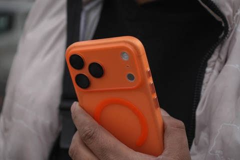 iPhone 17 Pro Max held by a person showing the home screen during the iOS 27 public beta test.