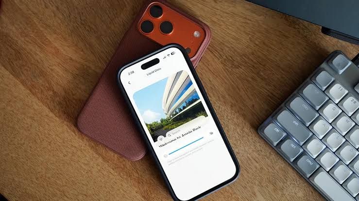A hand holding an iPhone displaying the new Liquid Glass slider settings menu in iOS 27.