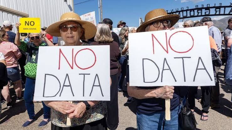 Protesters picket a local site with signs demanding an end to data center construction in their neighborhood.