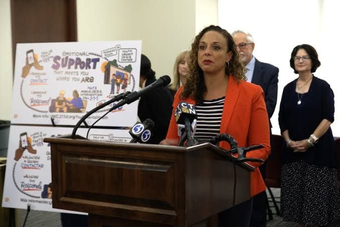 Laine Taylor speaking at a podium during a press conference about youth mental health resources in Connecticut.