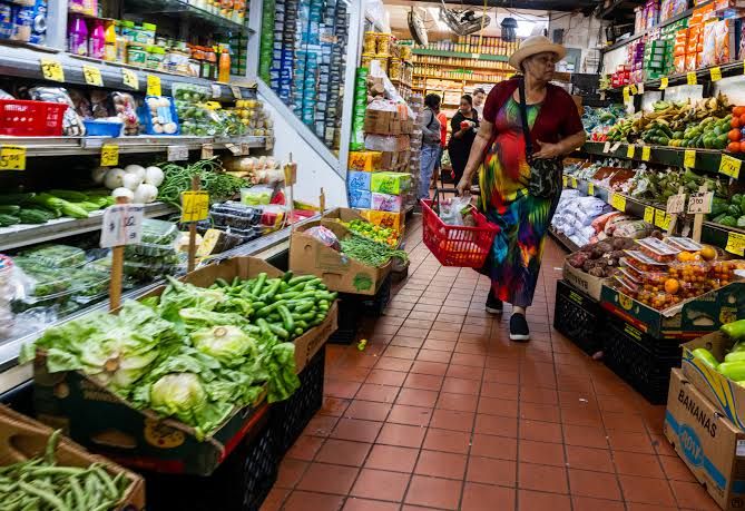 A grocery store cashier processes a gallon of milk at a checkout counter in Dallas during April 2026.