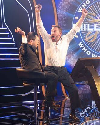 Ben Affleck and Jamie Ding celebrating with a large check on the Who Wants to Be a Millionaire set.