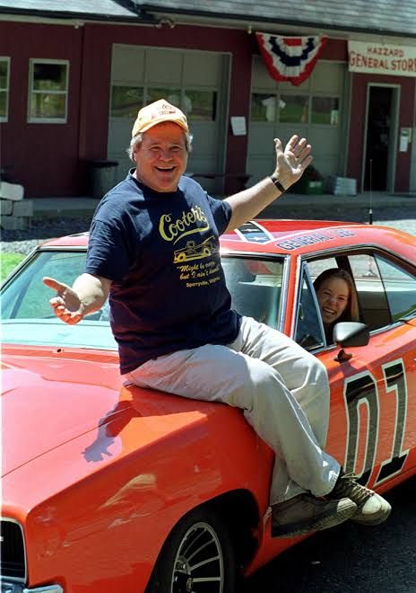 Ben Jones sitting on the orange General Lee Dodge Charger from the television series The Dukes of Hazzard.